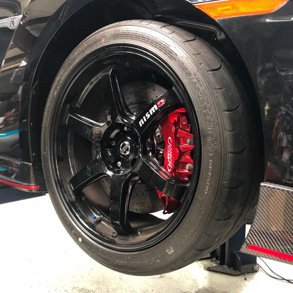 Close-up of a Nissan GT-R's black Nismo wheel, Dunlop tire, and red Jotech brake caliper.