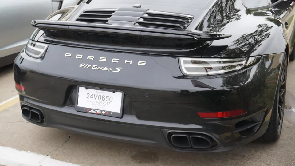 Rear view of a black Porsche 911 Turbo S showcasing its exhaust tips and rear spoiler.