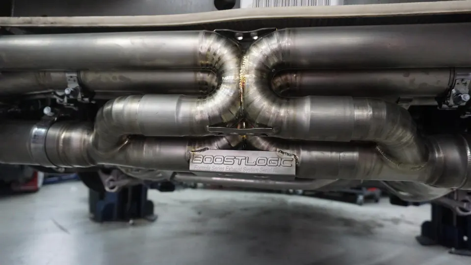 Close-up of a Boost Logic Formula Series titanium exhaust system installed on a performance car, showcasing the intricate welds.