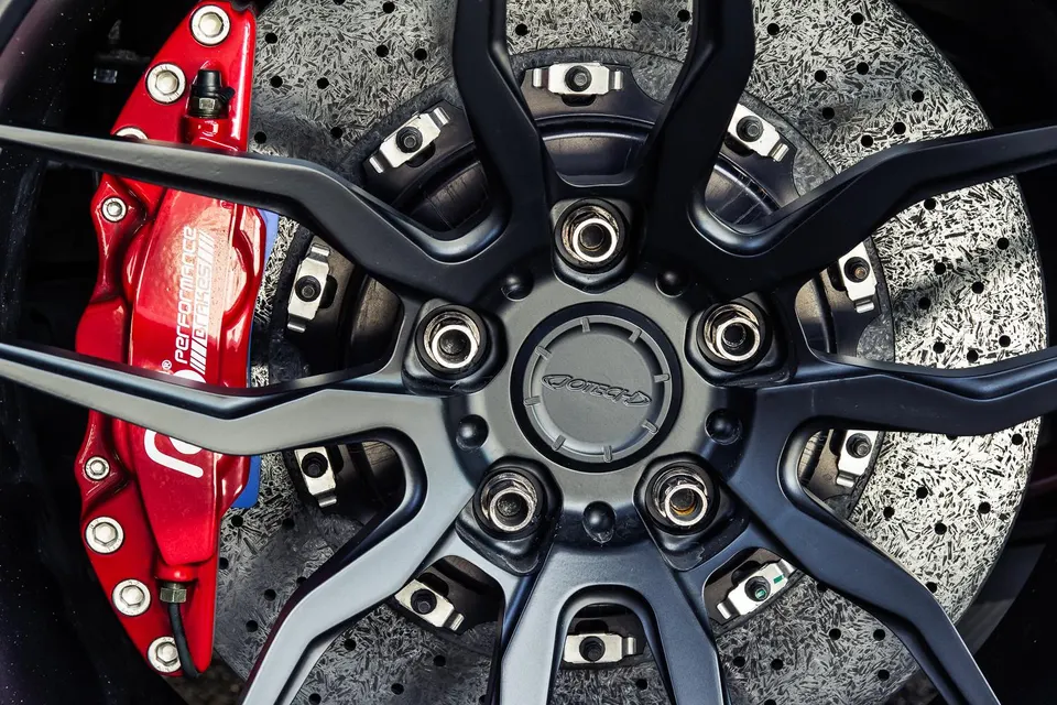 Close-up of a black forged wheel with a red AMG Performance brake caliper and a carbon ceramic rotor.