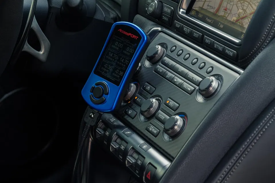 Cobb Accessport tuning device mounted on the center console of a Nissan GT-R interior.