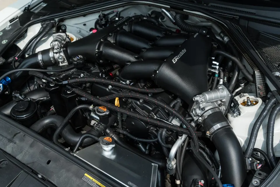 Close-up of a Nissan GT-R VR38DETT engine bay featuring a GReddy intake manifold and custom induction system.