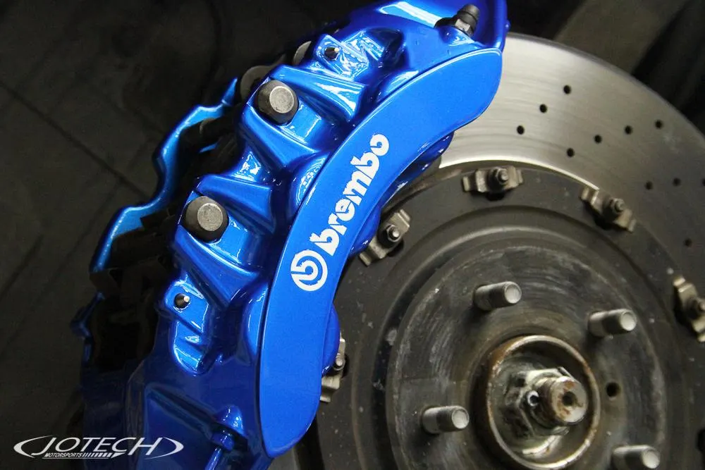 Close-up of a blue Brembo brake caliper and drilled rotor on a performance car, showcasing the braking system.