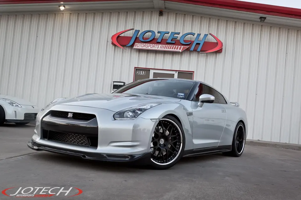 Silver Nissan GT-R with custom black wheels and a front splitter parked outside Jotech Motorsports.