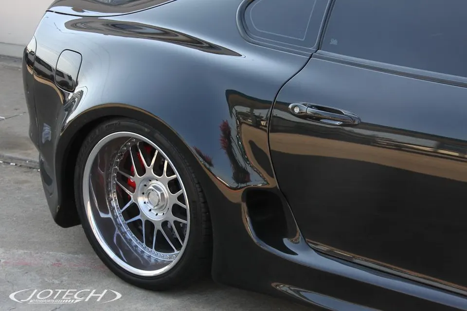 Close-up of a black Toyota Supra MK4's custom multi-spoke wheel with red brake calipers and widebody fender.