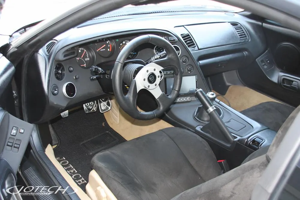 Interior view of a Jotech Motorsports built Toyota Supra with an aftermarket steering wheel, custom pedals, and gauges.