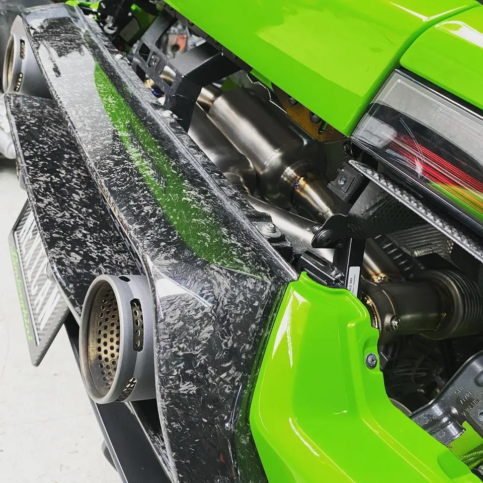 A close-up of a Lamborghini's custom exhaust system and forged carbon fiber rear bumper.