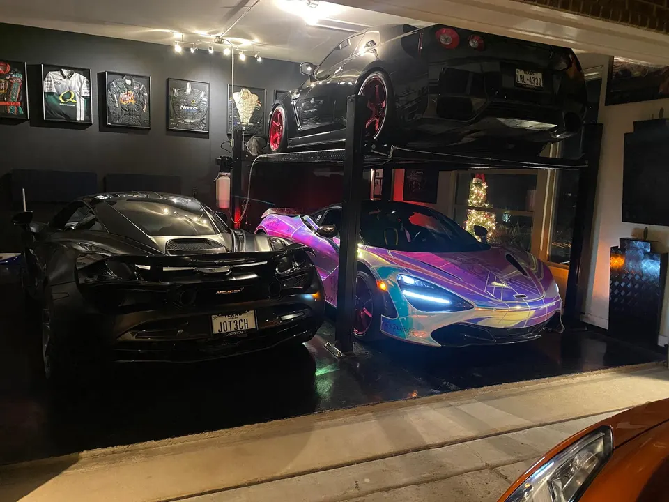 Three luxury sports cars, including a McLaren 720S and a Nissan GT-R, parked in a well-lit garage with a car lift.