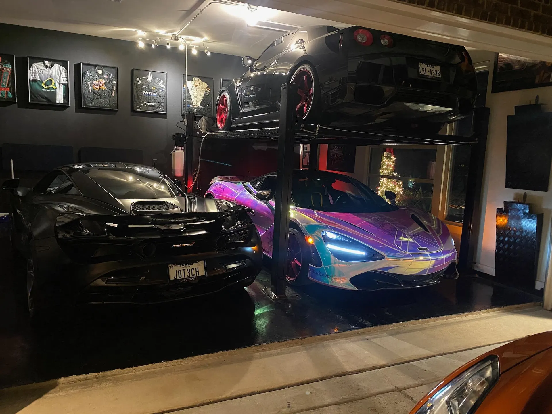 Three high-performance cars, including a black McLaren 720S, an iridescent McLaren, and a black Nissan GT-R on a lift, in a well-lit garage.