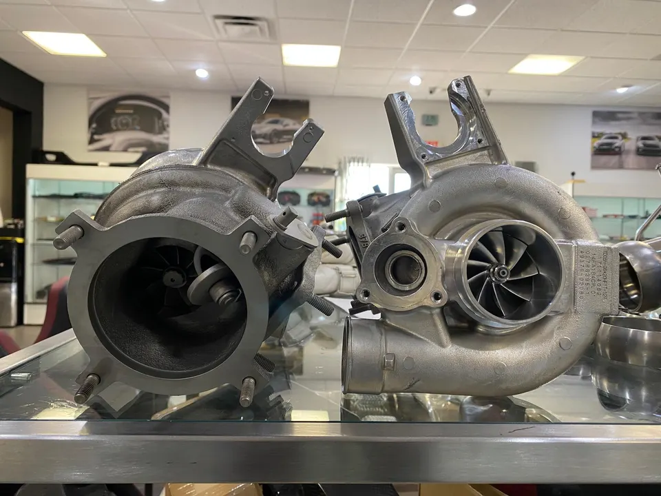 Two large performance turbochargers displayed side-by-side on a glass counter in a tuning shop.