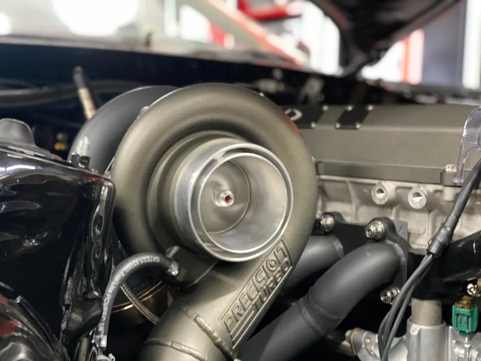 A close-up view of a Precision Turbo turbocharger installed in a high-performance engine bay.