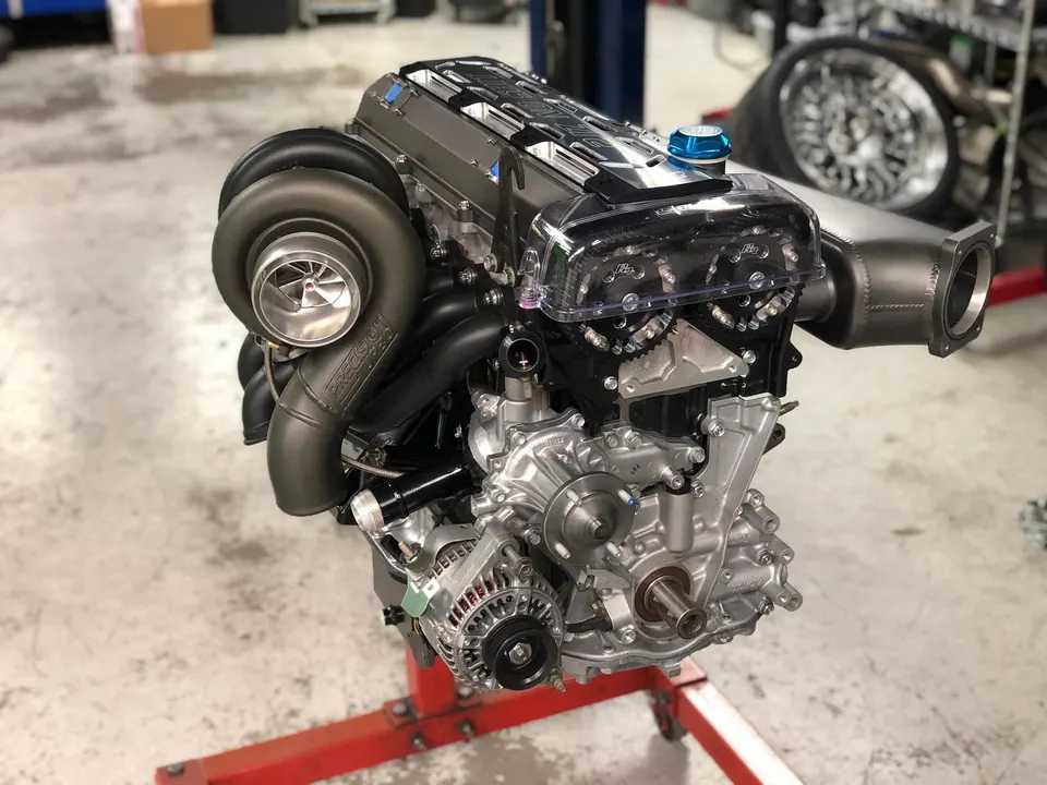 High-performance built engine with a large Precision turbocharger on a stand in a tuning shop.