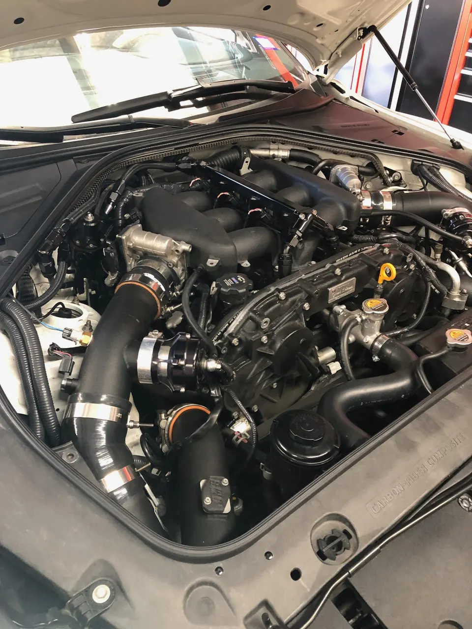 Close-up view of a modified Nissan GT-R engine bay featuring aftermarket induction and turbo components.