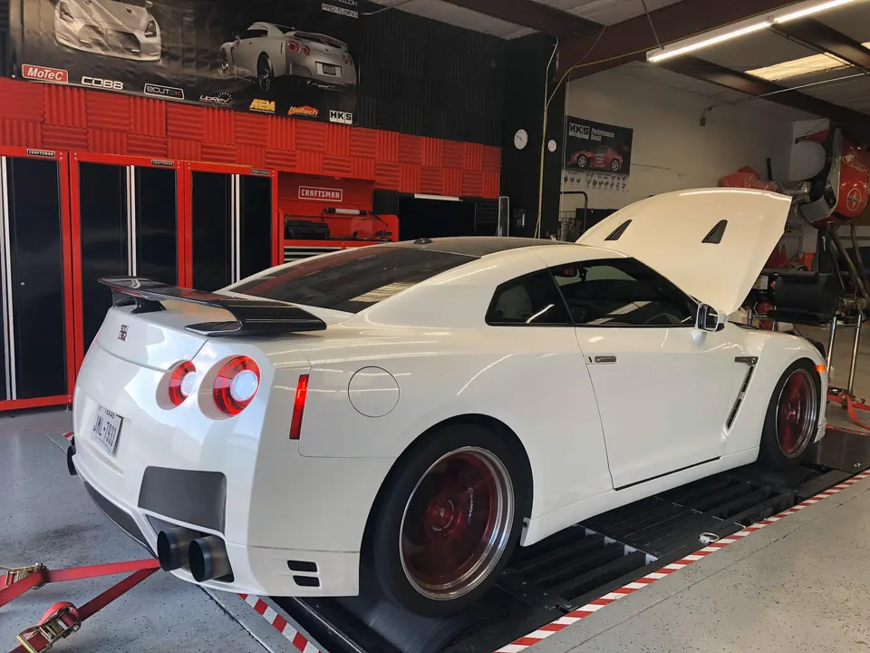 White Nissan GT-R strapped to a dyno in a performance tuning shop with the hood open
