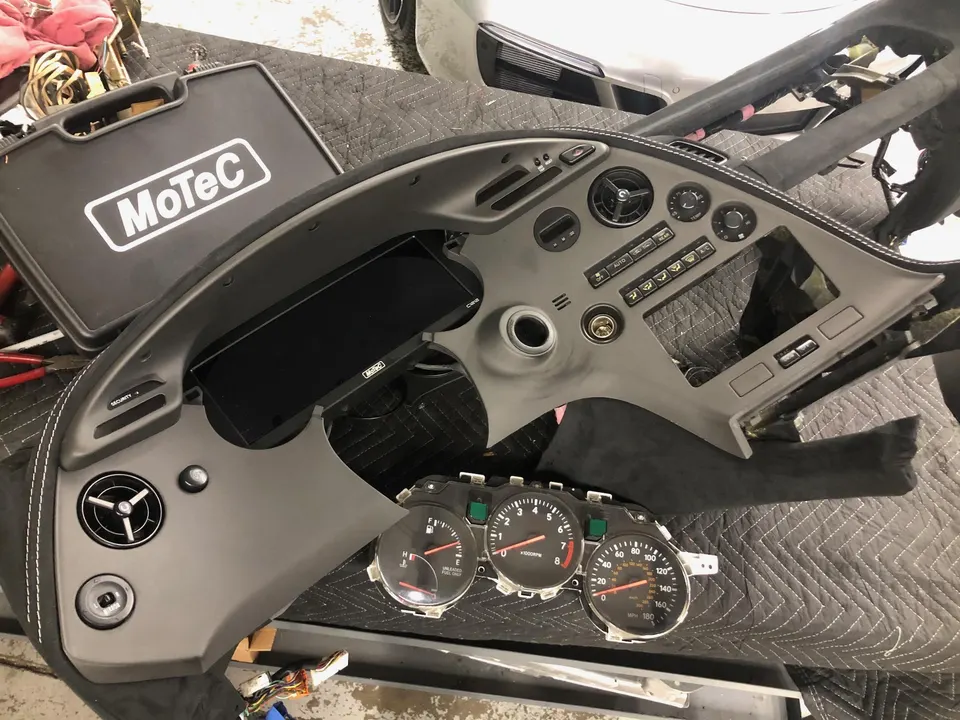 Toyota Supra dashboard and instrument cluster disassembled with a MoTeC digital dash unit during an electronics upgrade