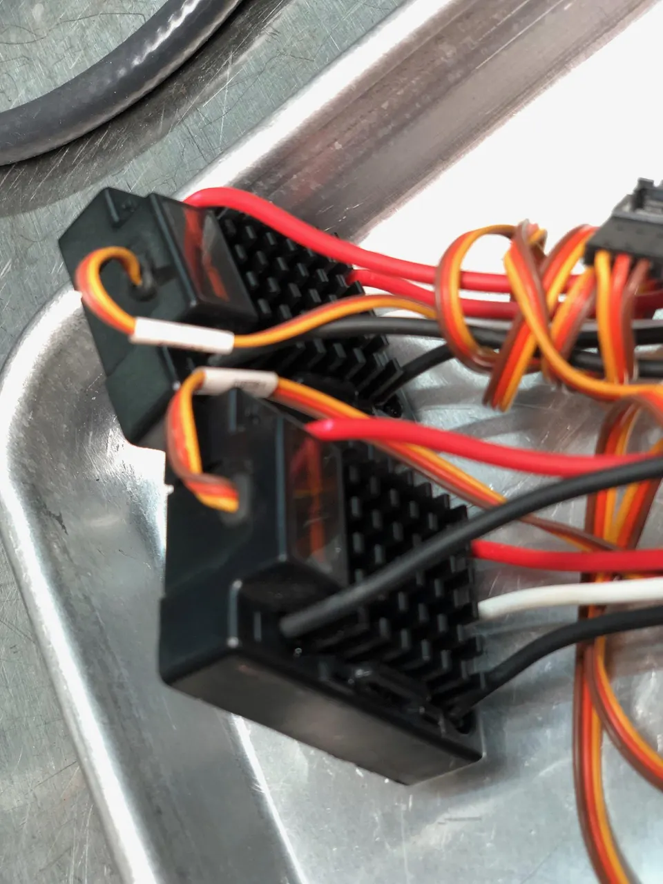Close-up of an electronic module with various colored wires and connectors on a metallic surface, likely for a performance car.