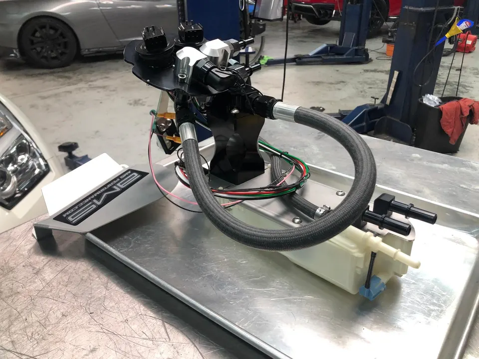AMS Performance fuel pump assembly with braided lines on a workbench in a tuning shop