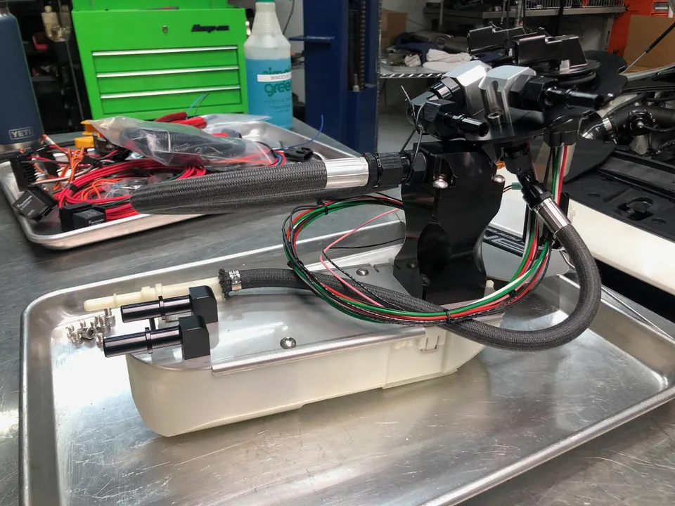 High-performance fuel system assembly with braided lines and wiring on a shop workbench, ready for installation.