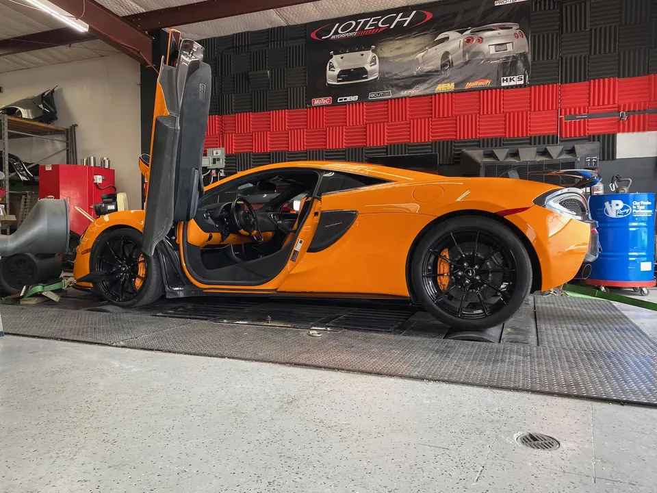 Orange McLaren supercar on a dyno at Jotech Motorsports for performance tuning and horsepower testing.