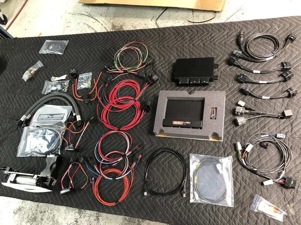 MoTeC M150 ECU, wiring harnesses, and other performance electronics laid out on a shop mat.