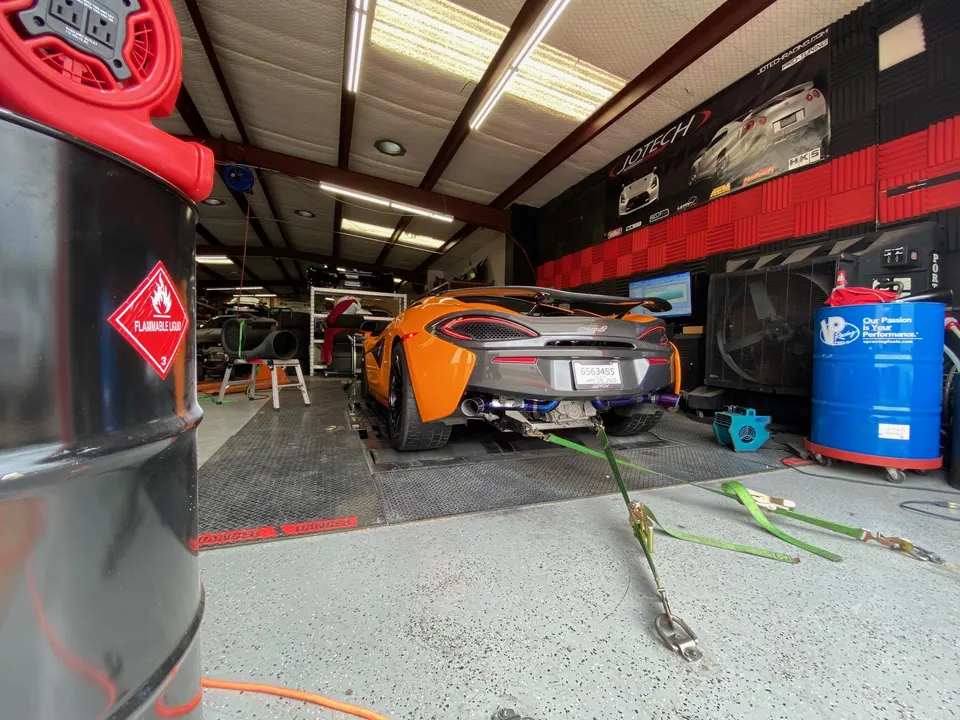Orange McLaren supercar on a dynamometer at Jotech Motorsports for performance tuning and testing.
