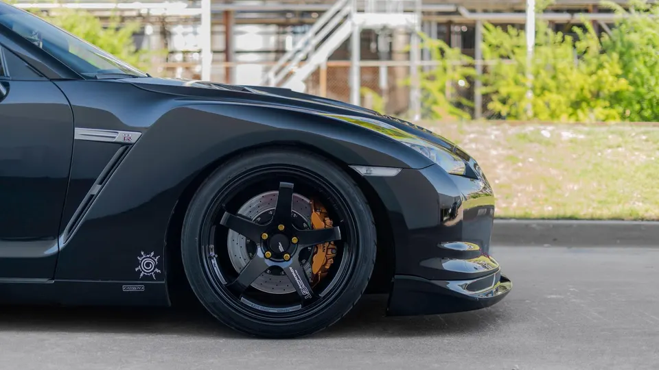 Side profile of a black Nissan GT-R with Advan GT wheels and gold performance brake calipers.