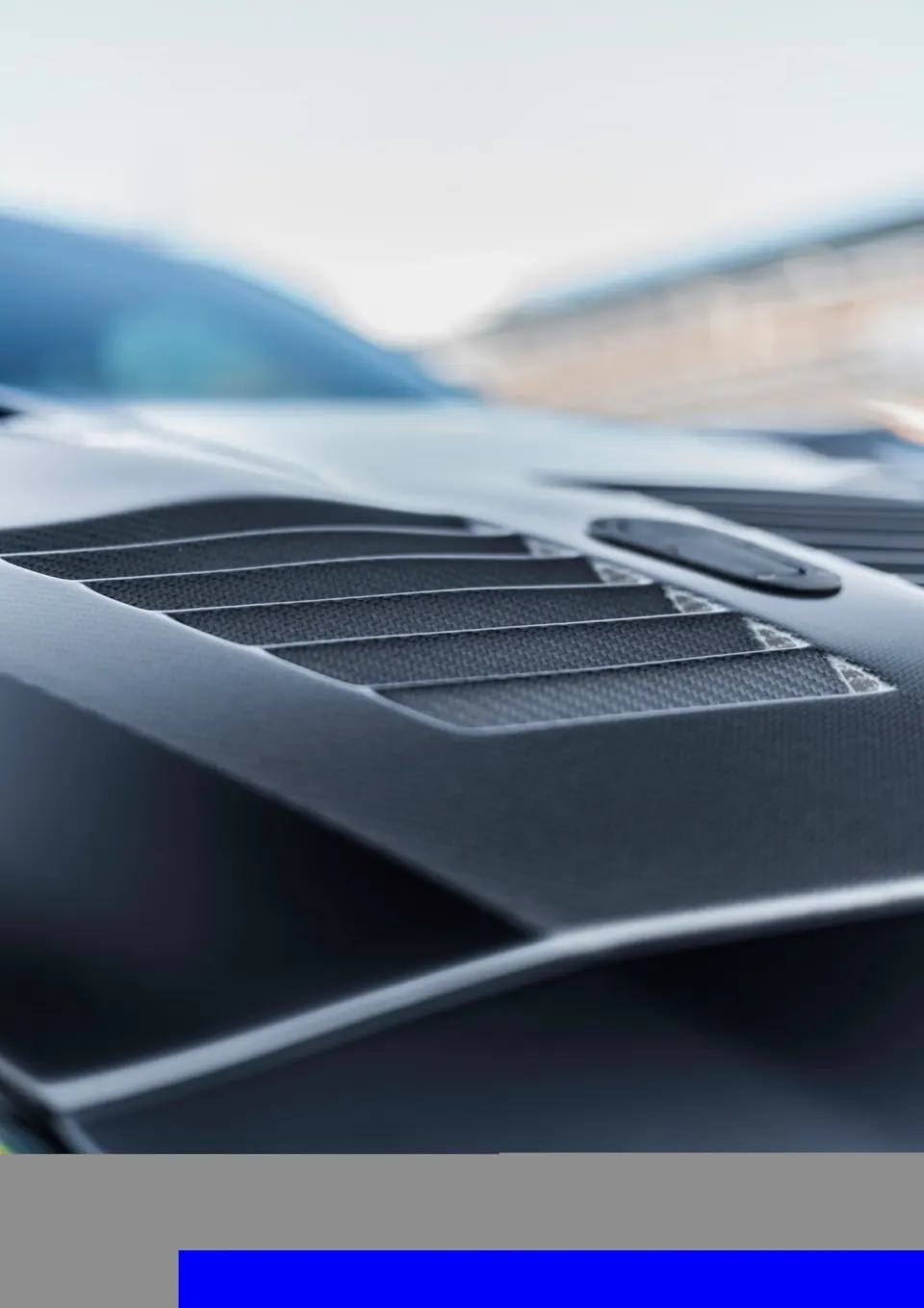 Close-up of a carbon fiber hood vent on a high-performance car, showcasing exterior aerodynamic details.