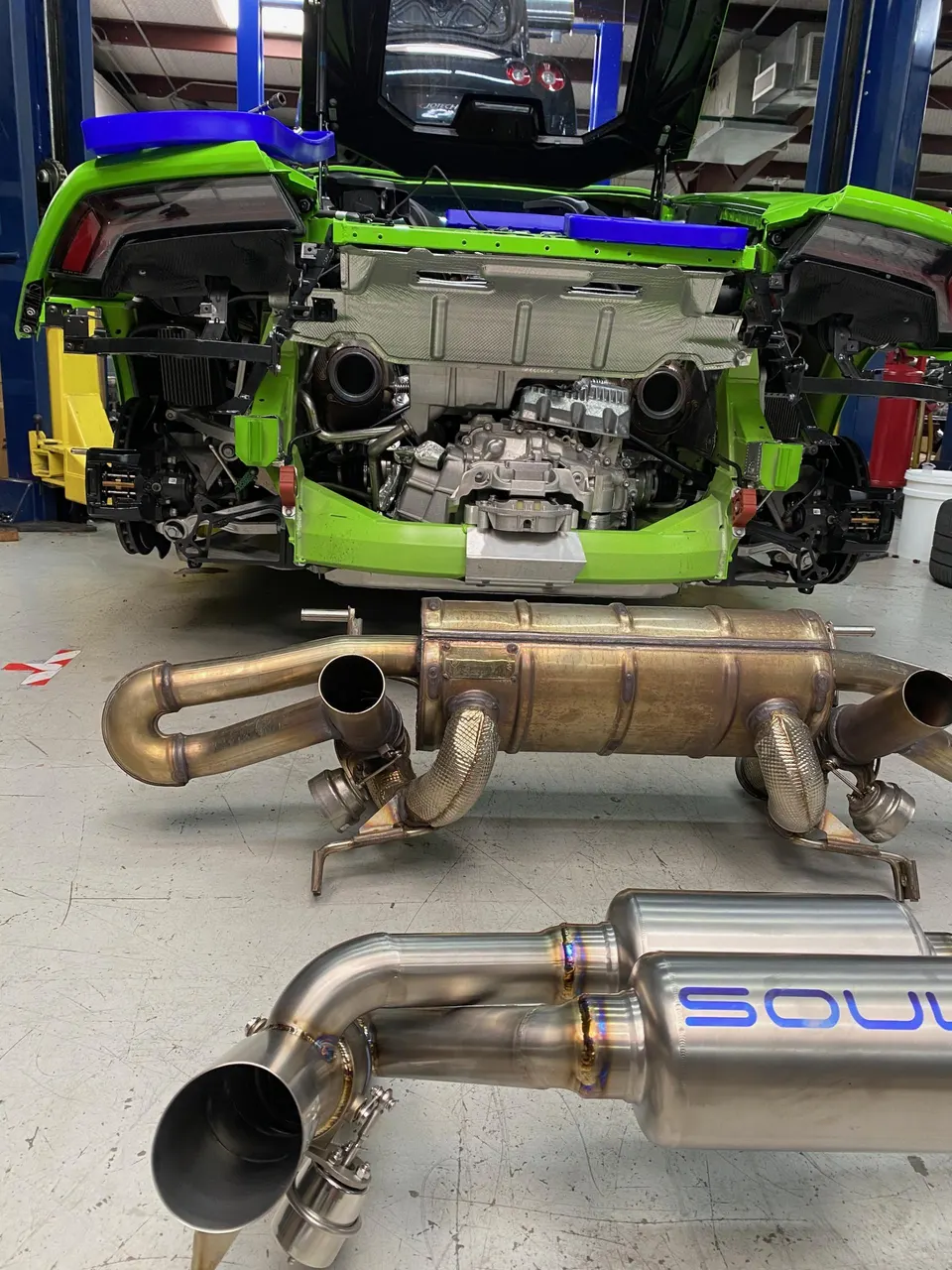 Lamborghini Huracan in a shop with its rear bumper removed, showing the engine and an aftermarket Soul Performance exhaust system.