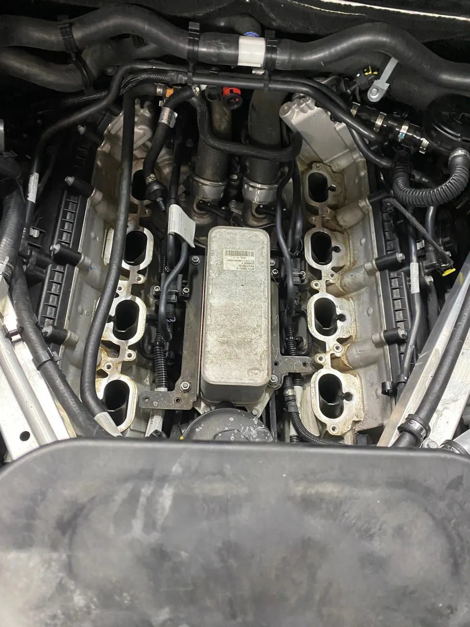 Detailed view of a car engine bay with the intake manifold removed, showing the engine block and various hoses during maintenance.