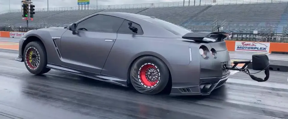 Grey Nissan GT-R with drag slicks and parachute at the starting line of Texas Motorplex drag strip