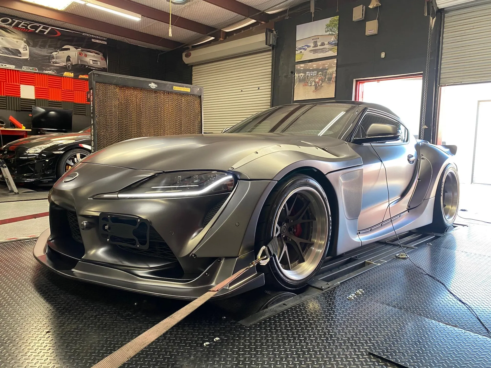 Matte grey widebody Toyota Supra A90 strapped to a dynamometer at Jotech Motorsports for performance tuning.