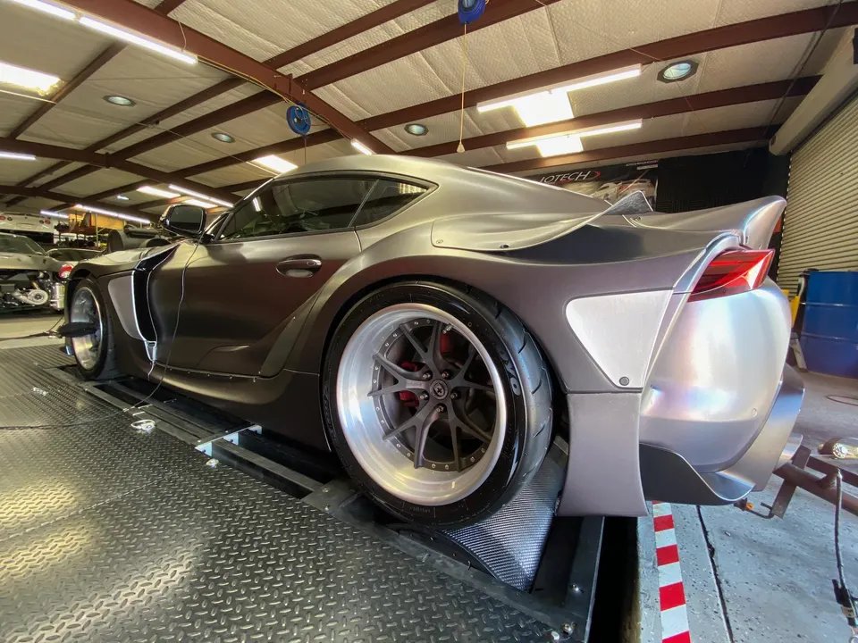 Widebody Toyota Supra on a dyno at Jotech Motorsports, showcasing custom wheels and aggressive aero.