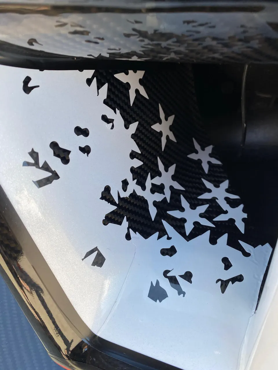 Close-up of a carbon fiber car panel with a white custom decal.