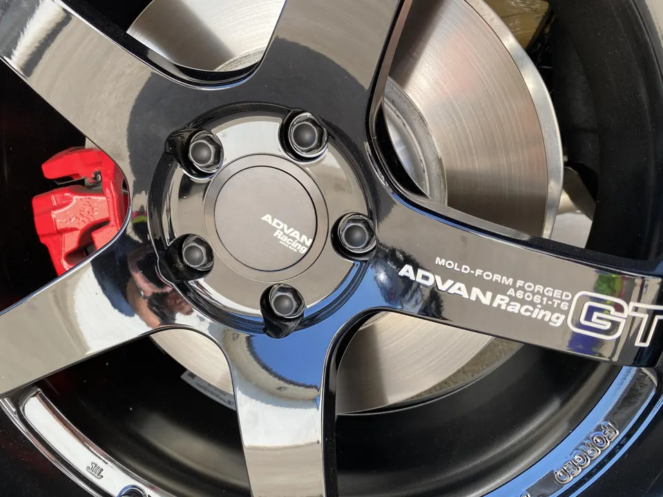 Close-up of an Advan Racing forged wheel with a red brake caliper and brake rotor.