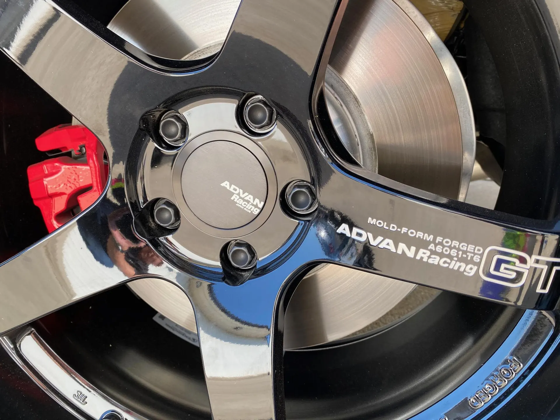 Close-up of an Advan Racing GT forged wheel with a red brake caliper and brake rotor.