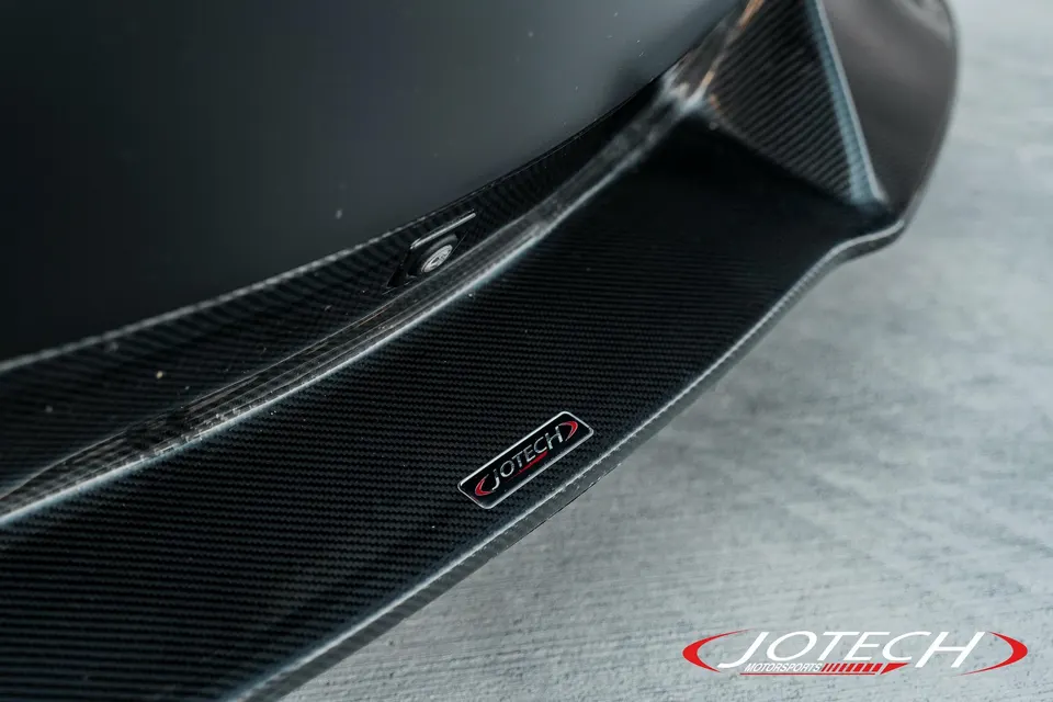 A close-up detail shot of a Jotech Motorsports carbon fiber exterior aerodynamic component on a performance car.