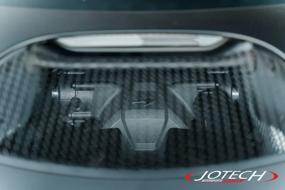 Close-up view of a car's throttle body and carbon fiber intake system, likely from a performance build by Jotech Motorsports.
