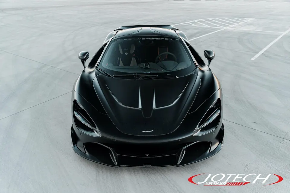A black McLaren 720S supercar parked on a concrete surface, showcasing its sleek front design.