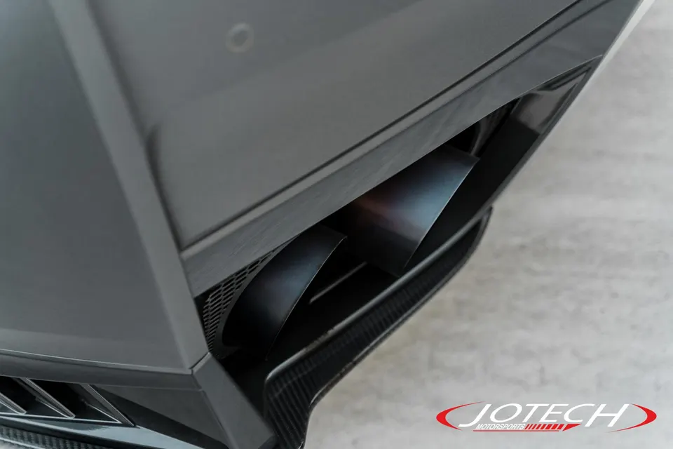 Close-up of a performance exhaust system with dual tips and carbon fiber rear diffuser on a high-performance car.