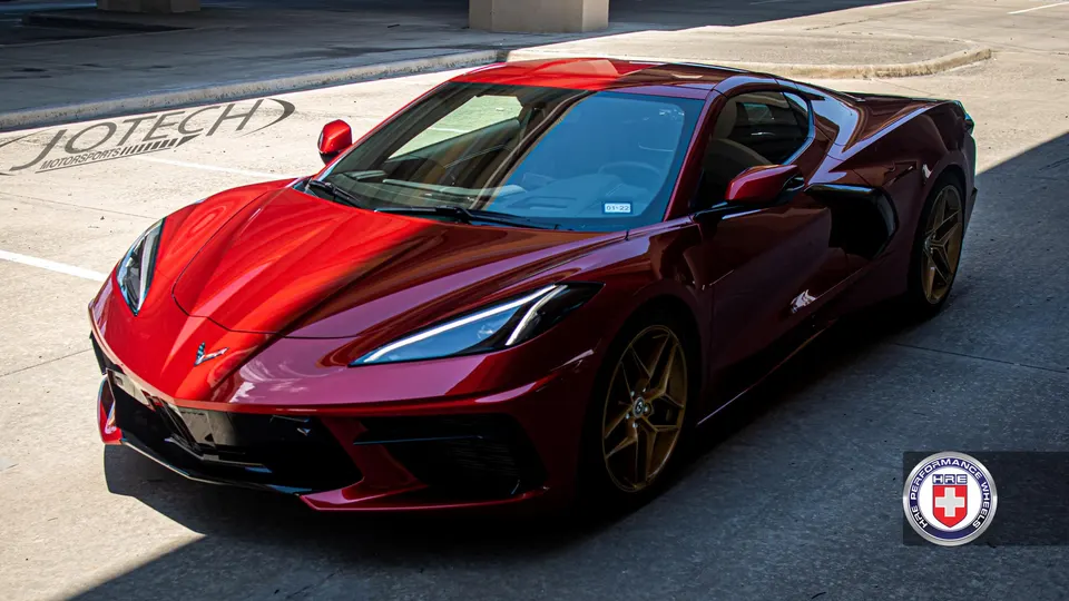 Red Chevrolet Corvette C8 with HRE Performance Wheels parked in a lot, showcasing its sleek design.