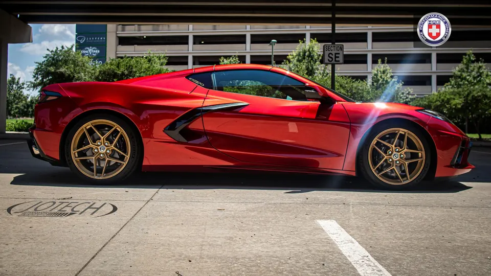 A red C8 Corvette with gold HRE performance wheels parked in a lot, featuring Jotech branding on the ground.