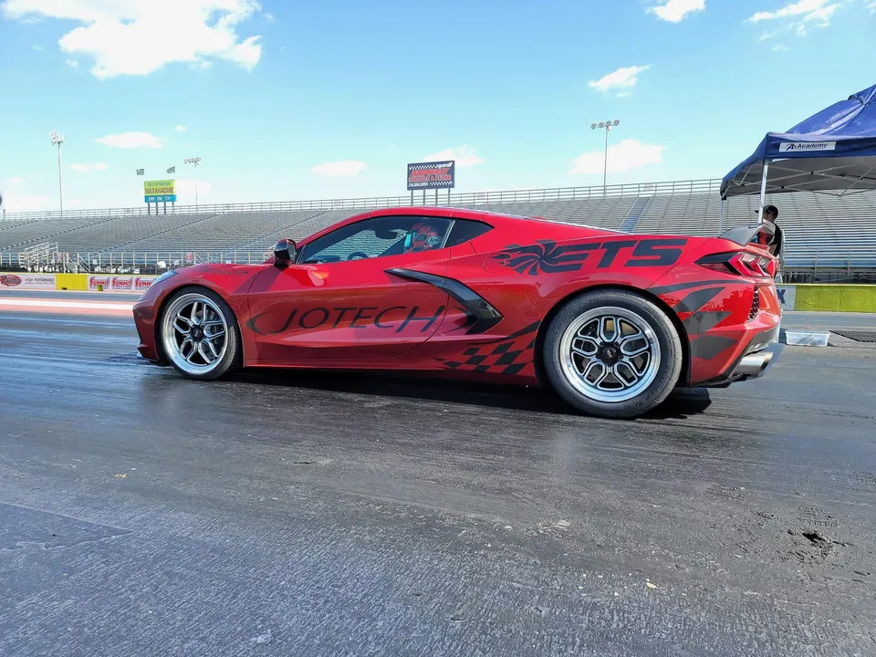 Red Corvette C8.R with Jotech and ETS livery on a drag strip, featuring aftermarket drag wheels.