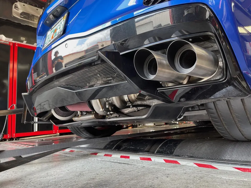 Rear view of a blue Corvette on a dyno, showcasing its twin-turbo setup and aftermarket exhaust system.