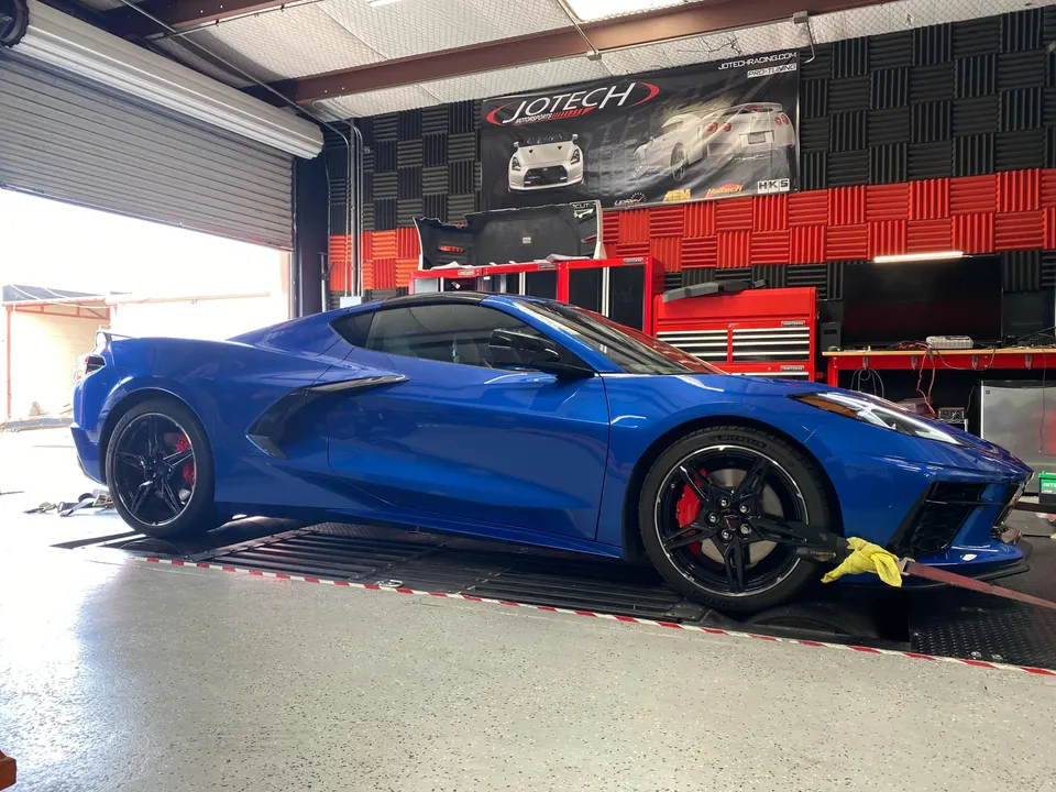 A blue Chevrolet Corvette C8 strapped to a dynamometer at Jotech Motorsports for performance tuning.