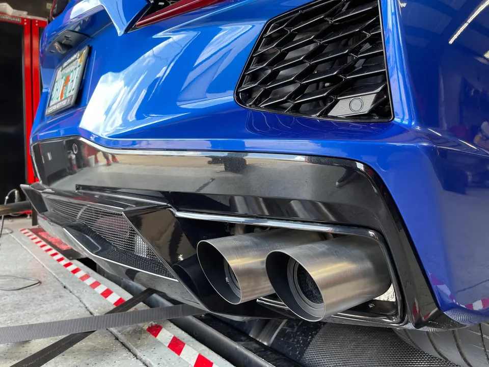 A blue C8 Corvette on a dyno, showcasing its custom exhaust system and rear diffuser.