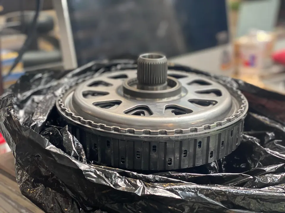 Close-up of a drivetrain component, possibly a transmission clutch pack or gear assembly, in a performance shop.