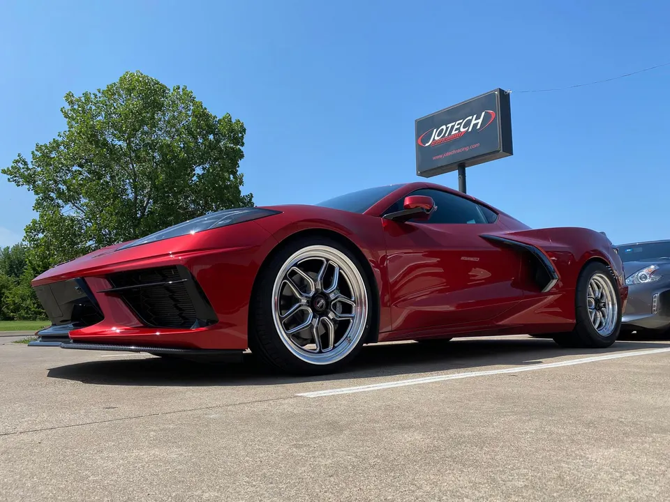 A red Chevrolet Corvette C8 with aftermarket drag wheels and a carbon fiber front splitter parked outside Jotech Motorsports.
