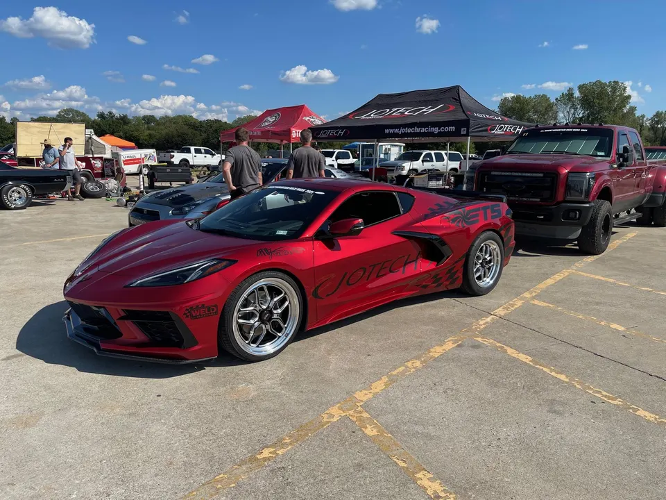 Red Corvette C8 drag car with Weld wheels and Jotech livery parked at a performance car event.