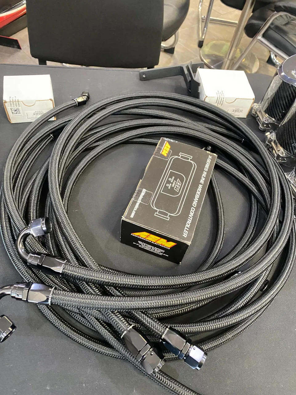 AEM X-Series Wideband Controller box and black braided AN hoses for a performance build.