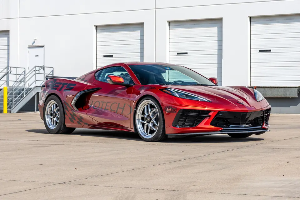 Red Chevrolet Corvette C8.R with drag wheels parked in front of a white building, showcasing Jotech Motorsports branding.